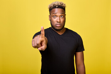 The surprised man points his finger with a serious expression on his face and rounded eyes. An indignant black person does not intend to do what he does not want and justifies his position