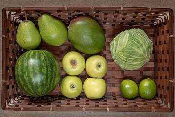 Rectangular basket with green fruit and vegetables: watermelon, apple, pear, mango, lime, cabbage