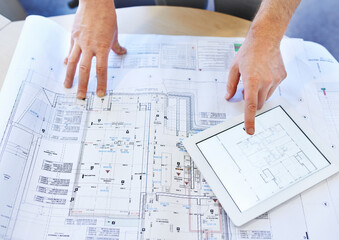 Going through the design with a fine-tooth comb. Shot of an architects hands examining blueprints...