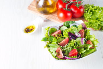 Fresh healthy vegetable salad made of cherry tomato, ruccola, arugula, feta, olives, cucumbers, onion and spices. Greek, Caesar salad in a white bowl on wooden background. 
