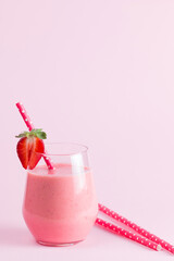 A glass of fresh strawberry smoothie on a pink background. Summer drink shake, milkshake and refreshment organic concept.