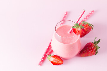 A glass of fresh strawberry smoothie on a pink background. Summer drink shake, milkshake and refreshment organic concept.