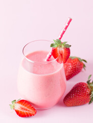 A glass of fresh strawberry smoothie on a pink background. Summer drink shake, milkshake and refreshment organic concept.