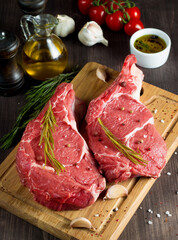 Raw fresh meat, beef and pork steak, ribeye, with rosemary, pepper and salt. Marbled beef cutlet with salt and spices.