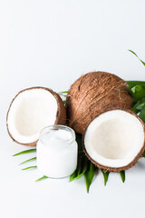 Ripe half cut coconut and cream with green leaves on a white isolated background. Healthcare and medical concept. Skin care.