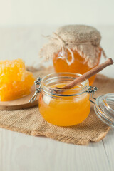 Honey dripping from a wooden honey dipper in a jar on wooden grey rustic background