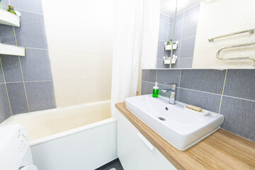 interior of a small compact bathroom with a mirror sink and wooden countertop