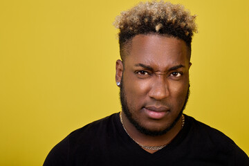 A young modern African American with an earring in his ear and curly hair with an irritated facial...