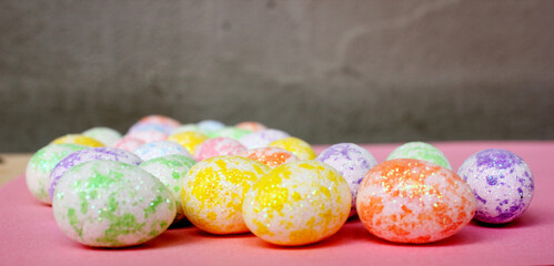 Easter eggs are multicolored on a pink background. Holiday. Eggs are small from foam plastic. Copy space. Side view. Easter. Toy.