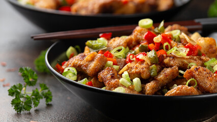 Stir fry salt and pepper pork loin with herbs in black bowl. Asian food