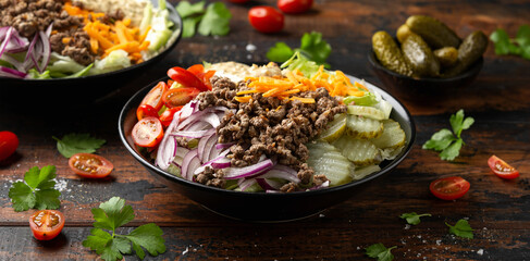 Cheeseburger, hamburger or burger keto salad with beef, fresh tomatoes, red onion, pickled gherkins, lettuce and home made sauce dressing