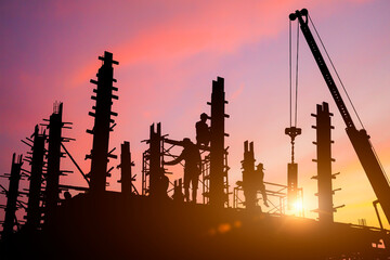 Silhouette of worker on building site, construction site with the sunset in the evening as the background.