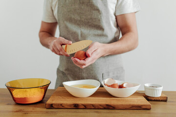 Man in apron cooking, in progress. Eggs, flour, salt on the table, cutting board and knife. Dough Ingredients.