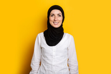 Young cheerful muslim woman in hijab on a yellow background. Banner