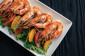 Grilled tiger prawns or shrimps with orange grapefruit and greens on a plate