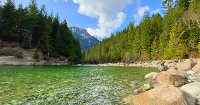 Establishing shot of majestic mountain river with mountain background in Vancouver, Canada, North America. Day time on April 2021. Still camera view. ProRes 422 HQ.