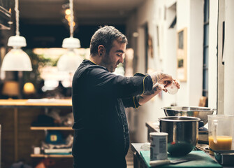 Just a little bit of salt. Shot of a focused chef preparing a dish in the kitchen of a restaurant.