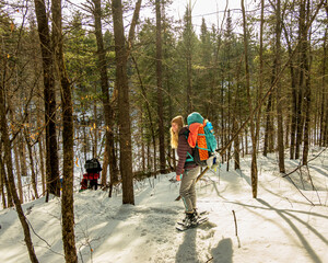 A young woman on snow shoes with a back pack off trail in the boreal forest. Shot outside Algonquin...