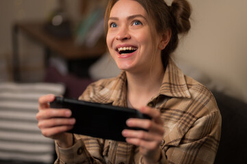 Joyful female gamer plays a video game on a portable game console. Close-up. Online games with...
