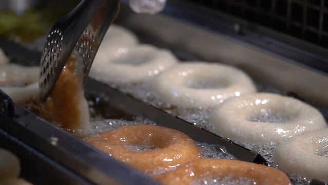 Frying homemade donuts in hot boiling oil, cooking greasy food. donuts
