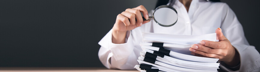 woman looking a magnifying glass to documents