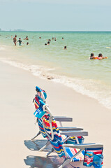 Obraz premium side view, medium distance of, two colorful, beach chairs, on the edge of a tropical shoreline, on a sunny afternoon
