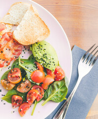 Scrambled eggs with bacon avocado and orange juice