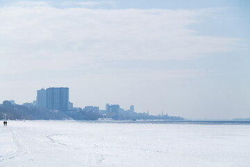 Naklejka premium city in the snow in winter. landscape of blue river and sky with sunlight and snow.