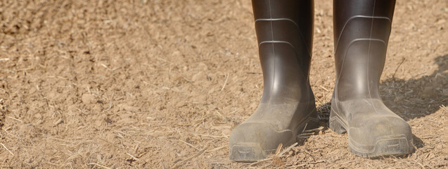 Farmer stands in rubber boots on his dusty, parched soil. Already in March it hardly rained and the...