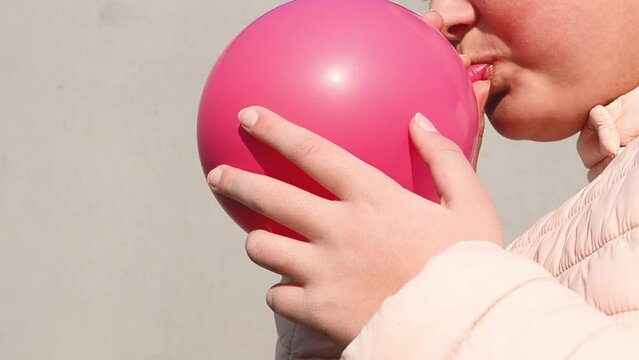 Close-up girl inflating pink balloon outdoors,video 4k
