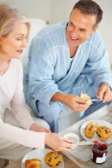 Obraz na płótnie Canvas Cheerful mature man and his wife having breakfast. Portrait of a cheerful mature man and his wife having breakfast.
