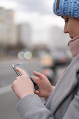 Woman working on her phone outdoors. Cold autumn weather