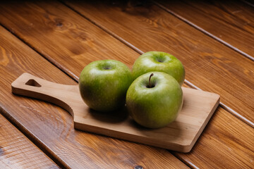 Green apples lie on a cutting board on the table