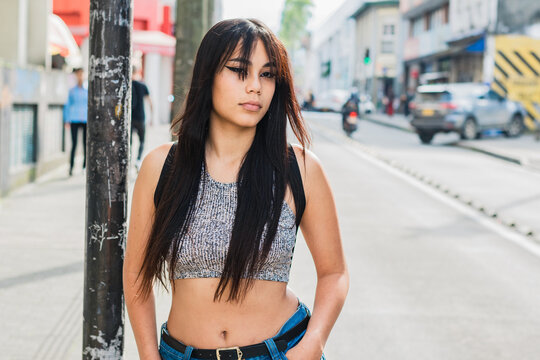 beautiful brown-skinned latina girl walking down the street with her eyes very serious and focused on the people walking down the street. university student waiting for transportation.