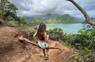 Woman sitting against ocean view while hiking.