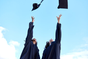 The famous graduation day tradition. Low angle shot of two attractive young female students...