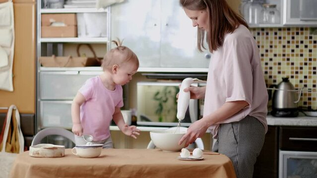 Little cute funny girl helping mother prepare pie cake in kitchen, baking homemade cookie together, happy family time