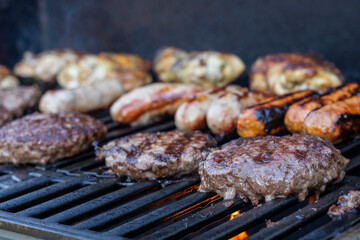 Burgers and sausages cooking on a BBQ grill