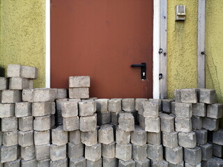 Gestapelte graue Pflastersteine auf dem Bürgersteig vor einer braunen Stahltür einer alten Werkstatt in Oerlinghausen bei Bielefeld am Hermannsweg im Teutoburger Wald in Ostwestfalen-Lippe