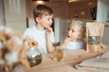 Small children gathered to drink tea and look at each other thoughtfully, with surprise.