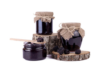 Sweet homemade blackberry jam in small glass jar with wooden spoon and fresh berries on a white...