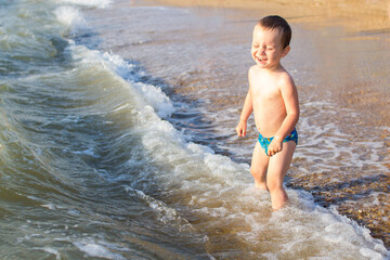 Fototapeta premium a little boy having fun in the sea on the waves