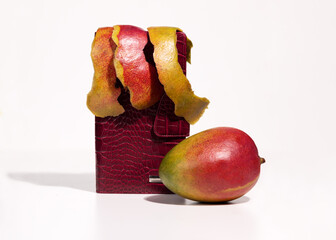 Red purse and mango fruit waste on white background. Vegan biodegradable lether from natural...