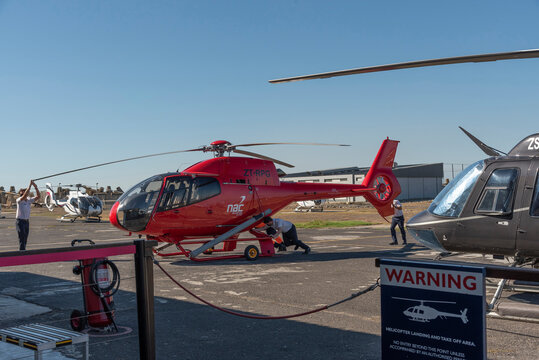 Cape Town South Africa. 2022. Helicopter crew moving a red chopper into the hangar at the V&A heliport, Cape Town.