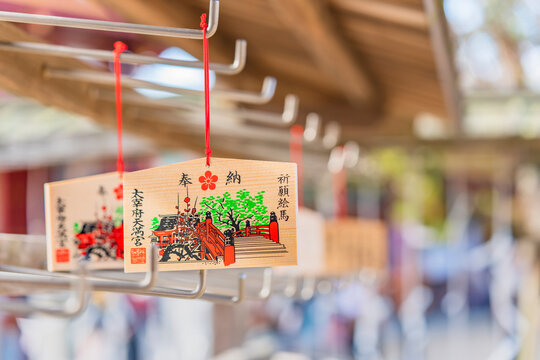 kyushu, japan - march 13 2022: Japanese wooden Ema plaques decorated with a drawing of the red Taiko Bashi bridge of Dazaifu shinto Shrine and adorned with a coat of arms depicting a plum blossom.