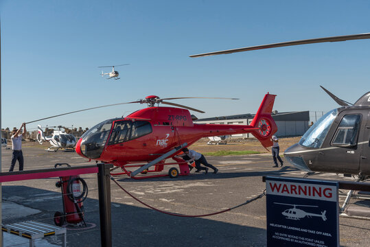 Cape Town South Africa. 2022. Helicopter crew moving a red chopper into the hangar at the V&A heliport, Cape Town.