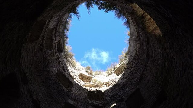 View from the bottom blue sky with white clouds surrounded by stone walls,hope for freedom and happiness, tower of a medieval fortress in the evening. City of Izborsk, Pskov region, Russia.