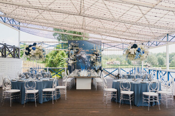 Coziness and style. Modern event design. Table setting at wedding reception. Floral compositions with beautiful flowers and greenery, candles, laying and plates on decorated table.