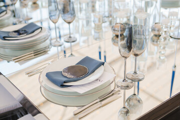 Coziness and style. Modern event design. Table setting at wedding reception. Floral compositions with beautiful flowers and greenery, candles, laying and plates on decorated table.