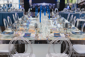 Coziness and style. Modern event design. Table setting at wedding reception. Floral compositions with beautiful flowers and greenery, candles, laying and plates on decorated table.